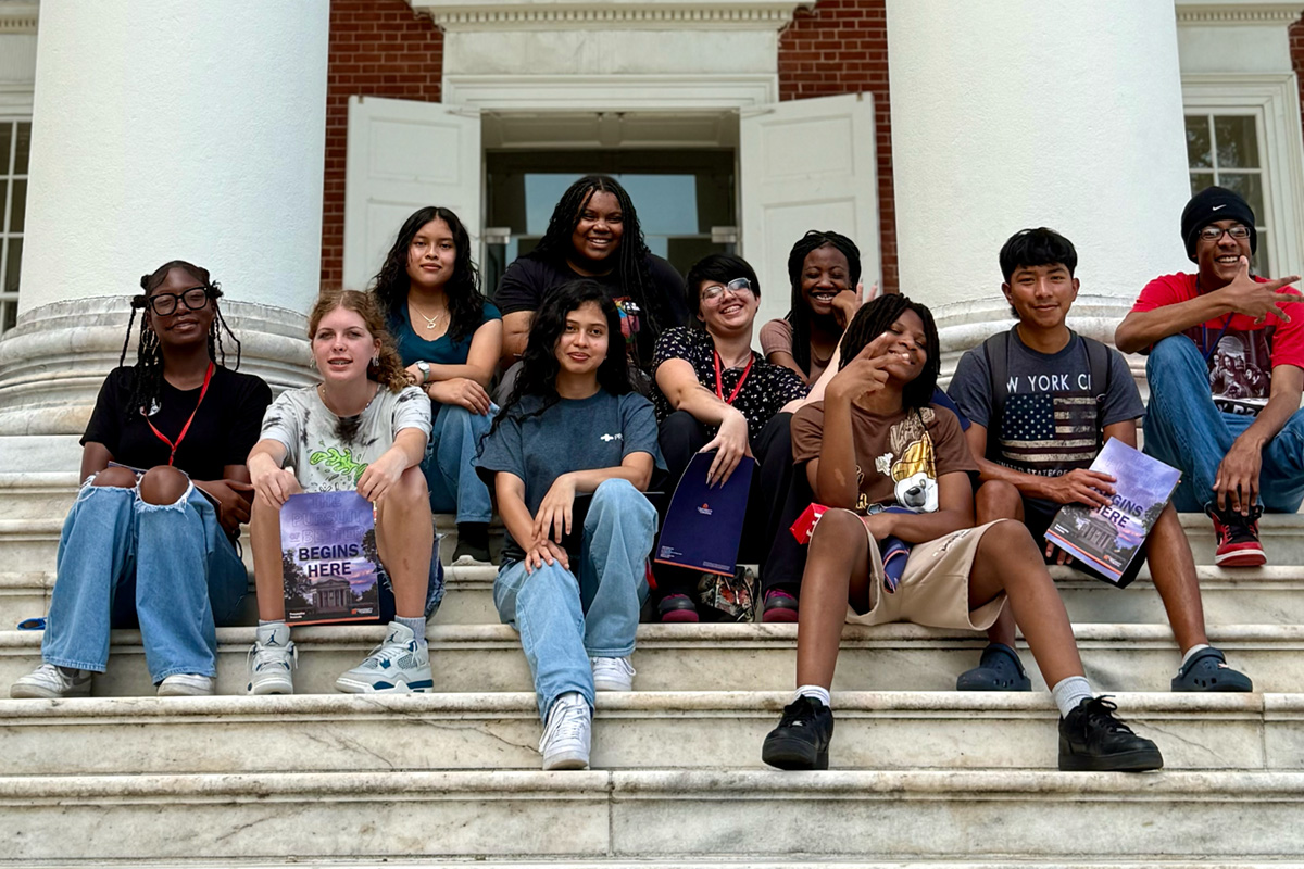 Dorm Days group photo teens sitting on steps of fancy college building